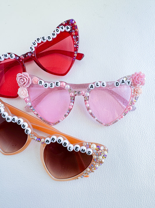 three pairs of pink and red sunglasses on a white surface