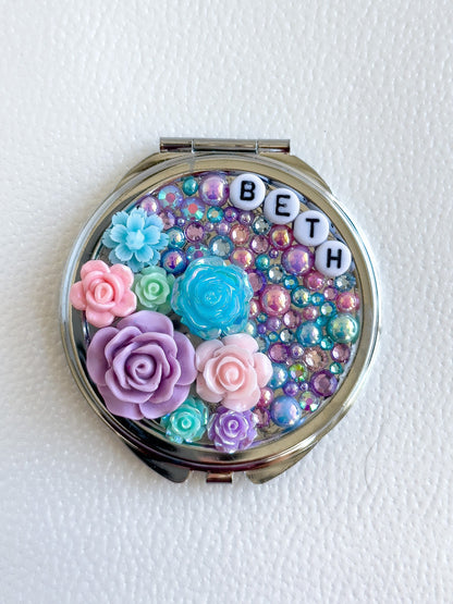 a compact compact case with flowers and letters on it