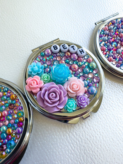 three compact compacts with beads and flowers on them