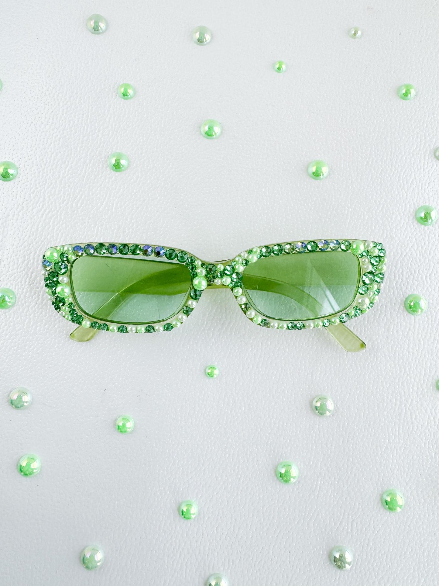 a pair of green sunglasses sitting on top of a white surface