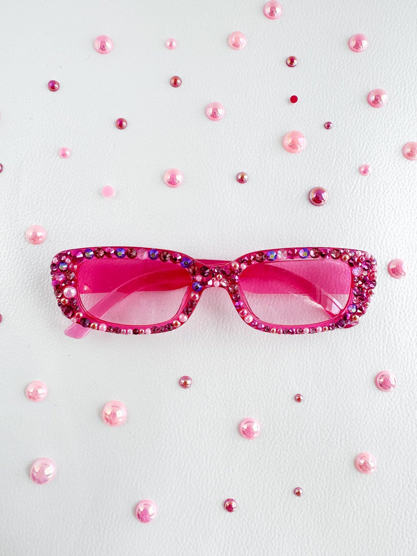 a pair of pink sunglasses sitting on top of a white surface