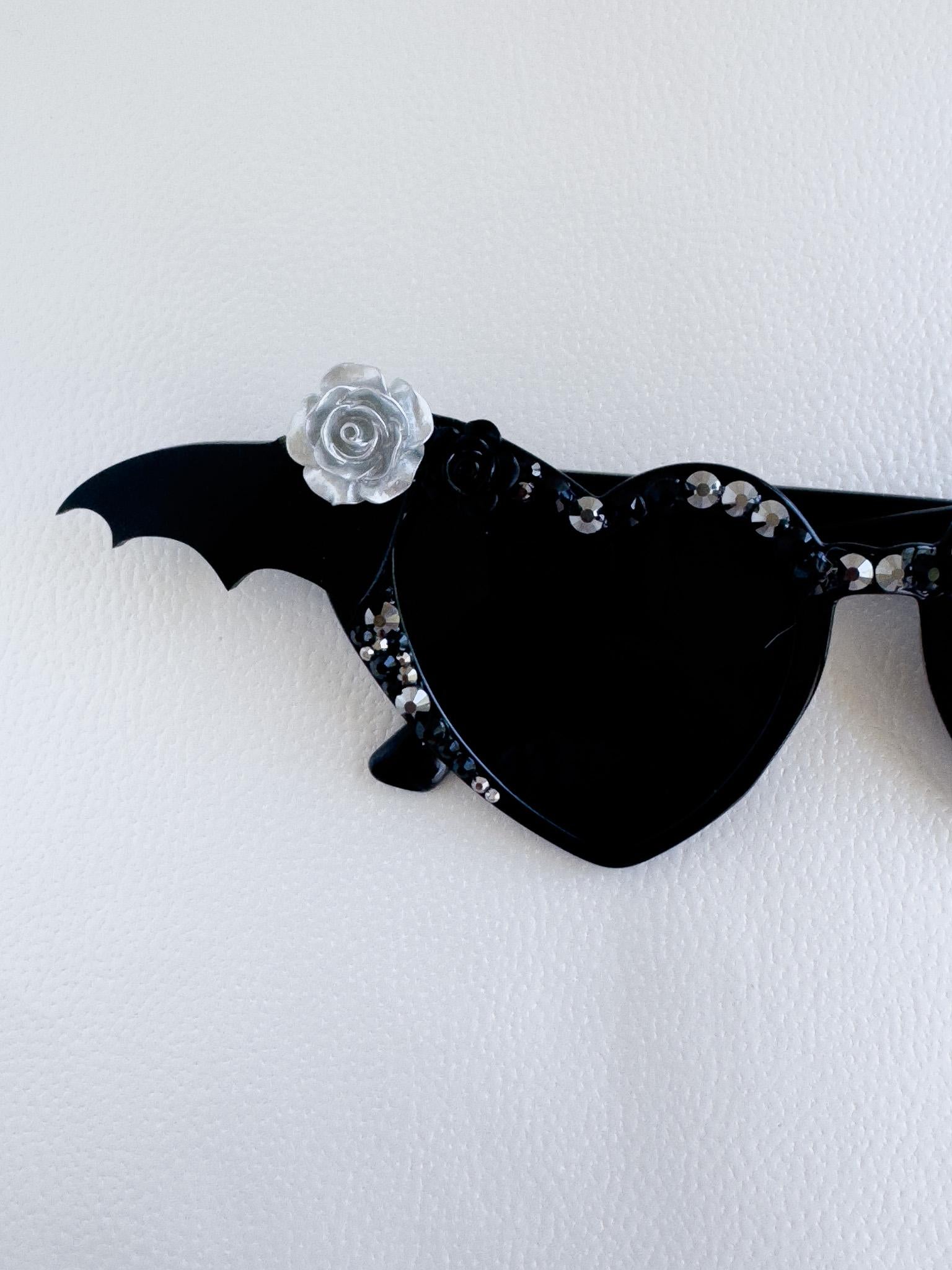 a black bat shaped brooch with a flower on it