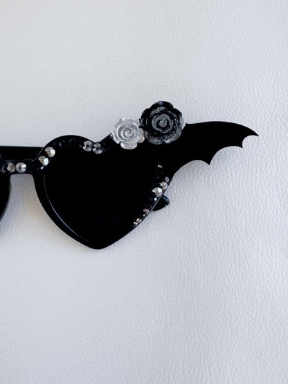 a pair of black sunglasses with a bat design on them