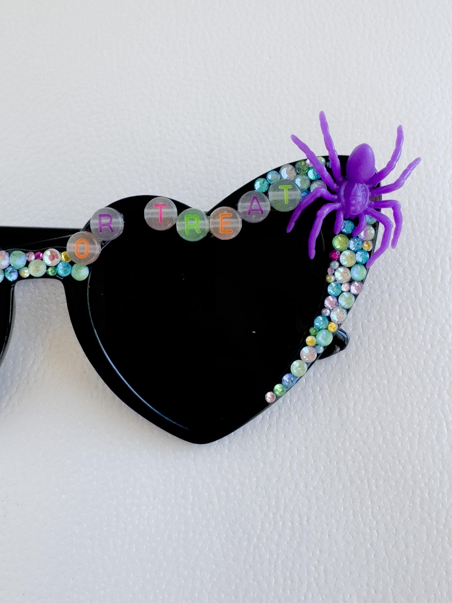 a black sunglasses with a purple spider on it