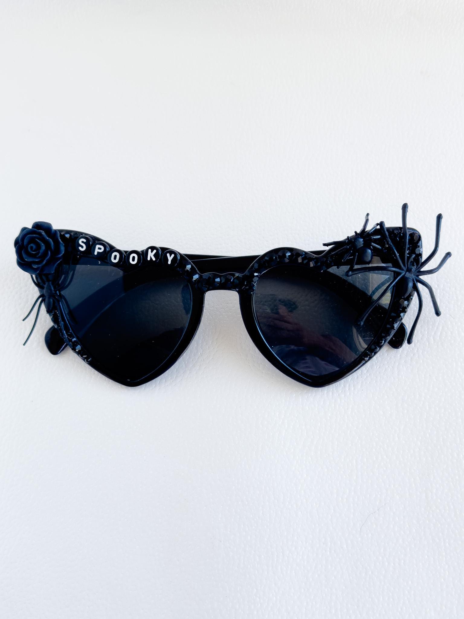 a pair of black sunglasses with a rose on the side